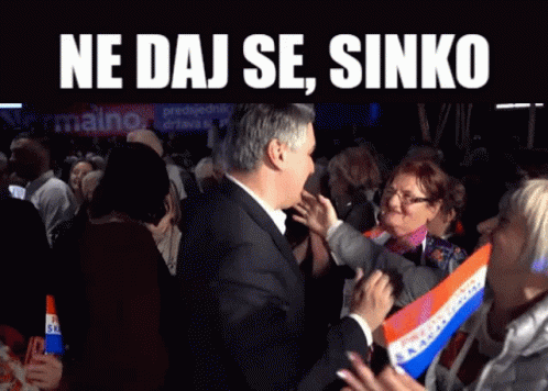 A Man In A Suit Stands In Front Of A Crowd With The Words Ne Daj Se Sinko On The Top GIF
