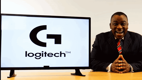 A Man In A Suit Stands In Front Of A Logitech Monitor GIF