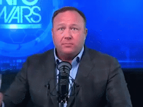 A Man In A Suit Stands In Front Of A Microphone In Front Of A Screen That Says No Wars GIF