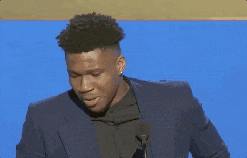 A Man In A Suit Stands In Front Of A Microphone GIF