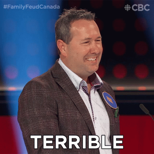A Man In A Suit Stands In Front Of A Microphone With The Word Terrible On His Face GIF