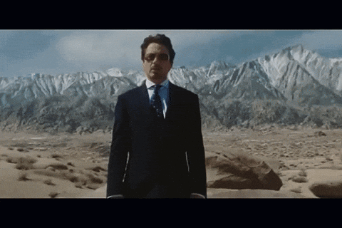 A Man In A Suit Stands In Front Of A Mountain Range GIF