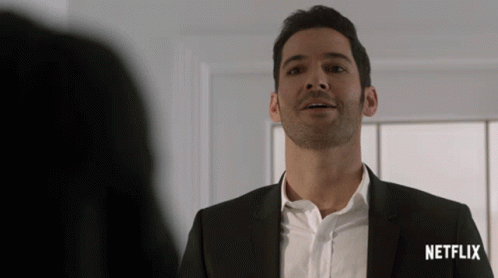 A Man In A Suit Stands In Front Of A Netflix Sign GIF
