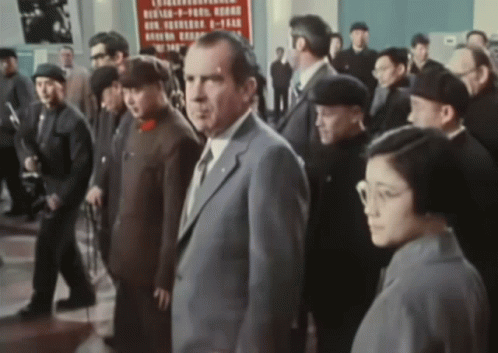 A Man In A Suit Stands In Front Of A Sign That Says ' Chinese ' On It GIF