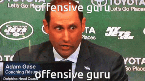 A Man In A Suit Stands In Front Of A Sign That Says Offensive Guru GIF