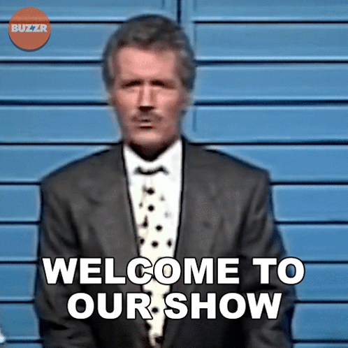 A Man In A Suit Stands In Front Of A Sign That Says Welcome To Our Show GIF