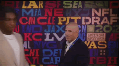 A Man In A Suit Stands In Front Of A Wall That Has The Word Draft On It GIF