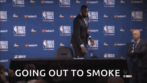 a man in a suit stands in front of a wall with nba finals written on it