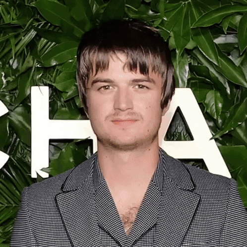 A Man In A Suit Stands In Front Of A Wall With The Letter A On It GIF