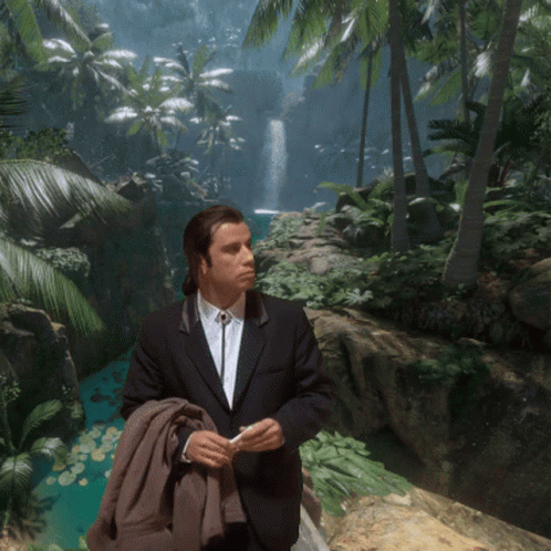 A Man In A Suit Stands In Front Of A Waterfall In The Jungle GIF