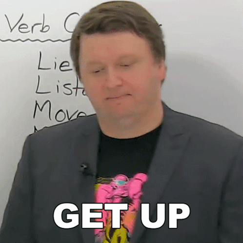 A Man In A Suit Stands In Front Of A White Board With The Words Get Up Written On It GIF