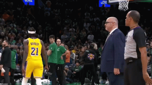 A Man In A Suit Stands Next To A Basketball Player Wearing The Number 21 GIF