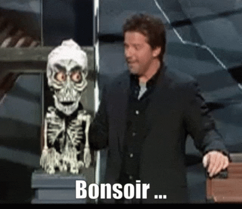 A Man In A Suit Stands Next To A Skeleton Statue And Says Bonsoir .. GIF