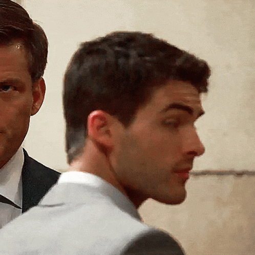 A Man In A Suit Stands Next To Another Man In A Suit And Tie GIF
