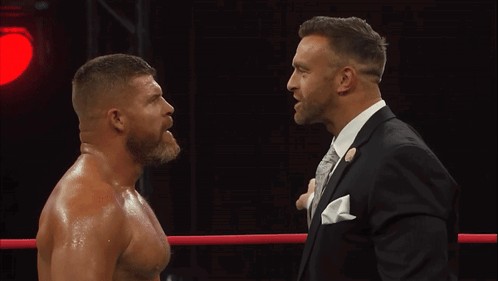 A Man In A Suit Stands Next To Another Man In A Suit GIF