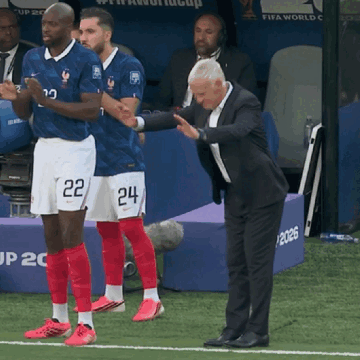 a man in a suit stands next to two soccer players wearing shorts that say 22 and 24
