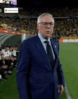 A Man In A Suit Stands On A Soccer Field GIF