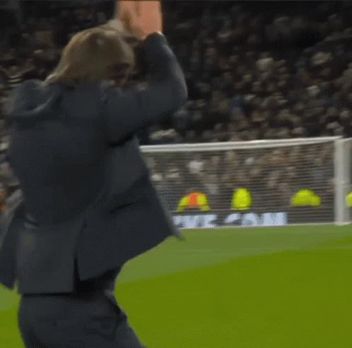 A Man In A Suit Stands On A Soccer Field In Front Of A Heineken Ad GIF