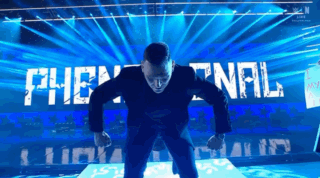 A Man In A Suit Stands On A Stage In Front Of A Sign That Says The Final GIF