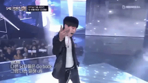 a man in a suit stands on a stage with a microphone and says go back