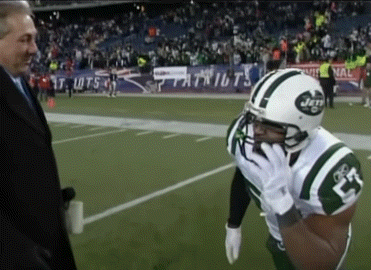 A Man In A Suit Talks To A Football Player Wearing A Jets Jersey GIF