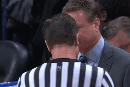 A Man In A Suit Talks To A Referee Who Is Wearing A Striped Shirt With The Letter S On It GIF