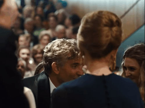 A Man In A Suit Talks To A Woman In A Blue Dress GIF