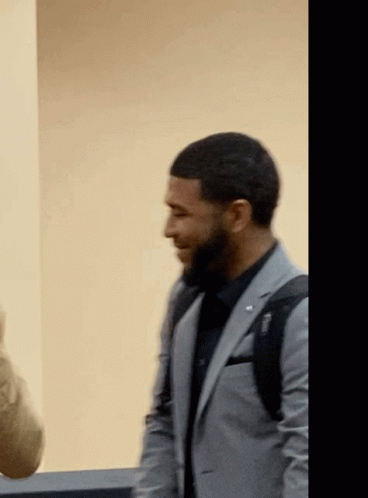 A Man In A Suit With A Backpack On His Back Is Smiling GIF