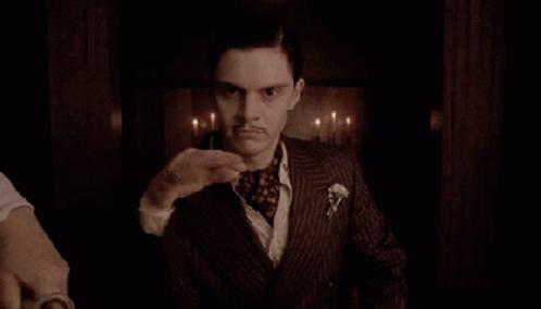 A Man In A Suit With A Mustache Waves His Hand GIF