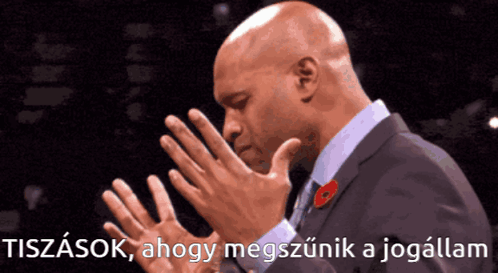 A Man In A Suit With A Poppy On His Lapel Holds His Hands Together In Prayer GIF