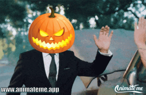 A Man In A Suit With A Pumpkin On His Head Is Waving GIF
