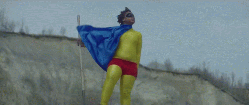 A Man In A Superhero Costume Holds A Stick GIF