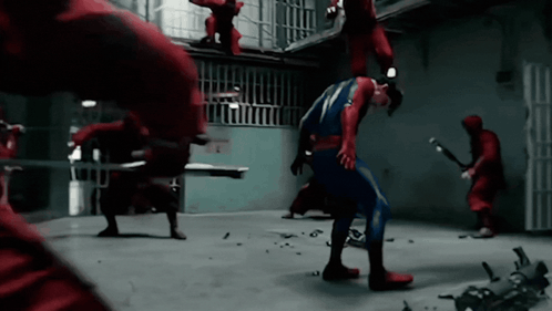 A Man In A Superhero Costume Is Being Attacked By A Group Of Men In Red GIF