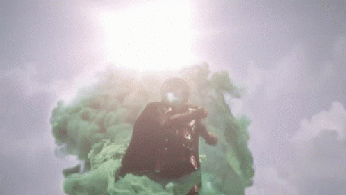 A Man In A Superhero Costume Is Flying Through A Cloud Of Green Smoke GIF
