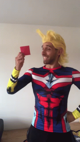 A Man In A Superhero Costume Is Holding Up A Red Card GIF