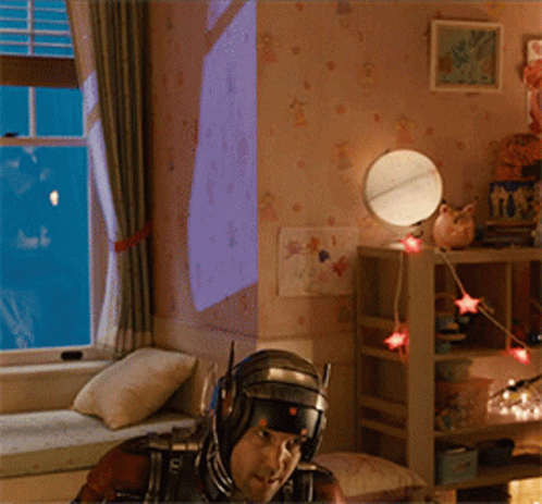 Man In Superhero Costume Sitting On Window Sill GIF