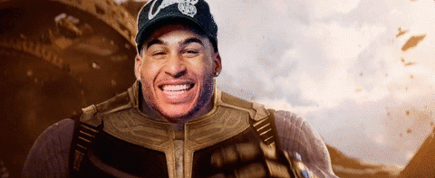 A Man In A Superhero Costume Is Smiling While Wearing A Hat With The Letter C On It . GIF
