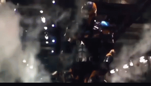 A Man In A Superhero Costume Is Standing In A Dark Room With Smoke Coming Out Of It GIF