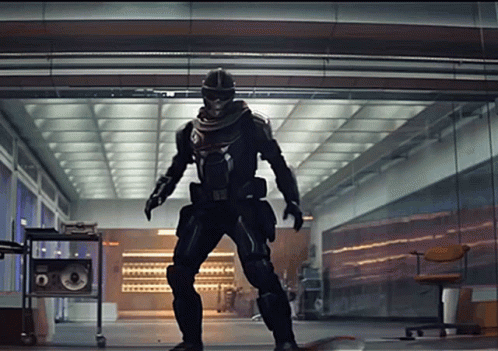 A Man In A Superhero Costume Is Standing In A Hallway GIF