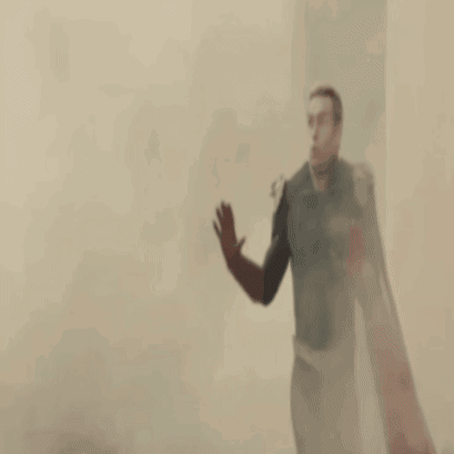 A Man In A Superhero Costume Is Standing In Front Of A Banner GIF