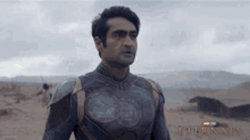 A Man In A Superhero Costume Is Standing In The Desert Looking At Something . GIF