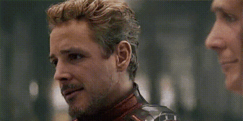 a man in a superhero costume is talking to another man in a room .