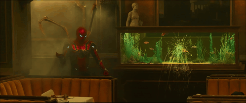 A Man In A Superhero Costume Stands In Front Of A Fish Tank GIF