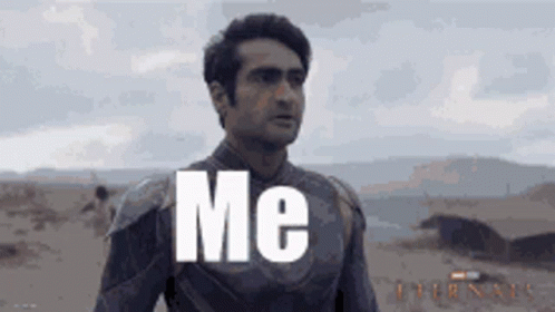 A Man In A Superhero Suit Is Standing In The Desert With The Words `` Me '' Written On His Chest . GIF