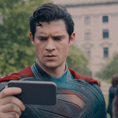 a man in a superman costume is taking a picture of himself with a cell phone