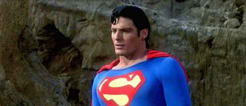 A Man In A Superman Costume Stands In Front Of A Rock GIF