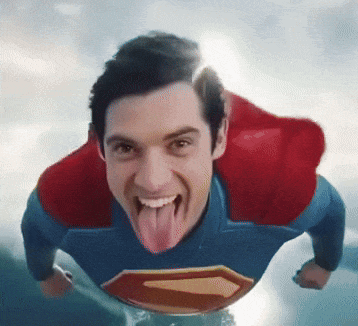 A Man In A Superman Costume With His Tongue Out GIF