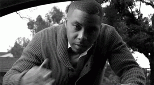 A Man In A Sweater And Tie Is Standing In A Car . GIF
