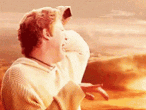 A Man In A Sweater Is Laughing In Front Of A Desert . GIF