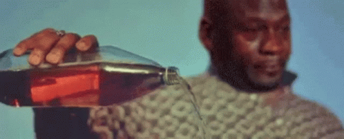 A Man In A Sweater Is Pouring A Bottle Of Coke Into A Glass . GIF
